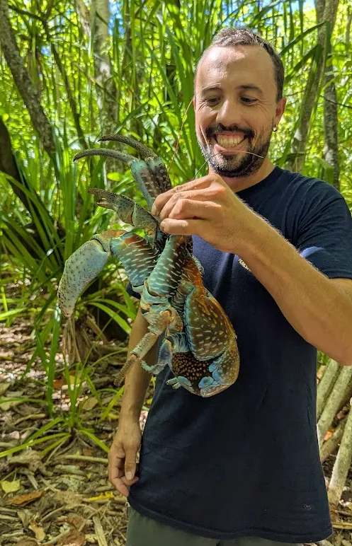 Captain Anders holding a coconut crab caught on a Palmerston motu hunt