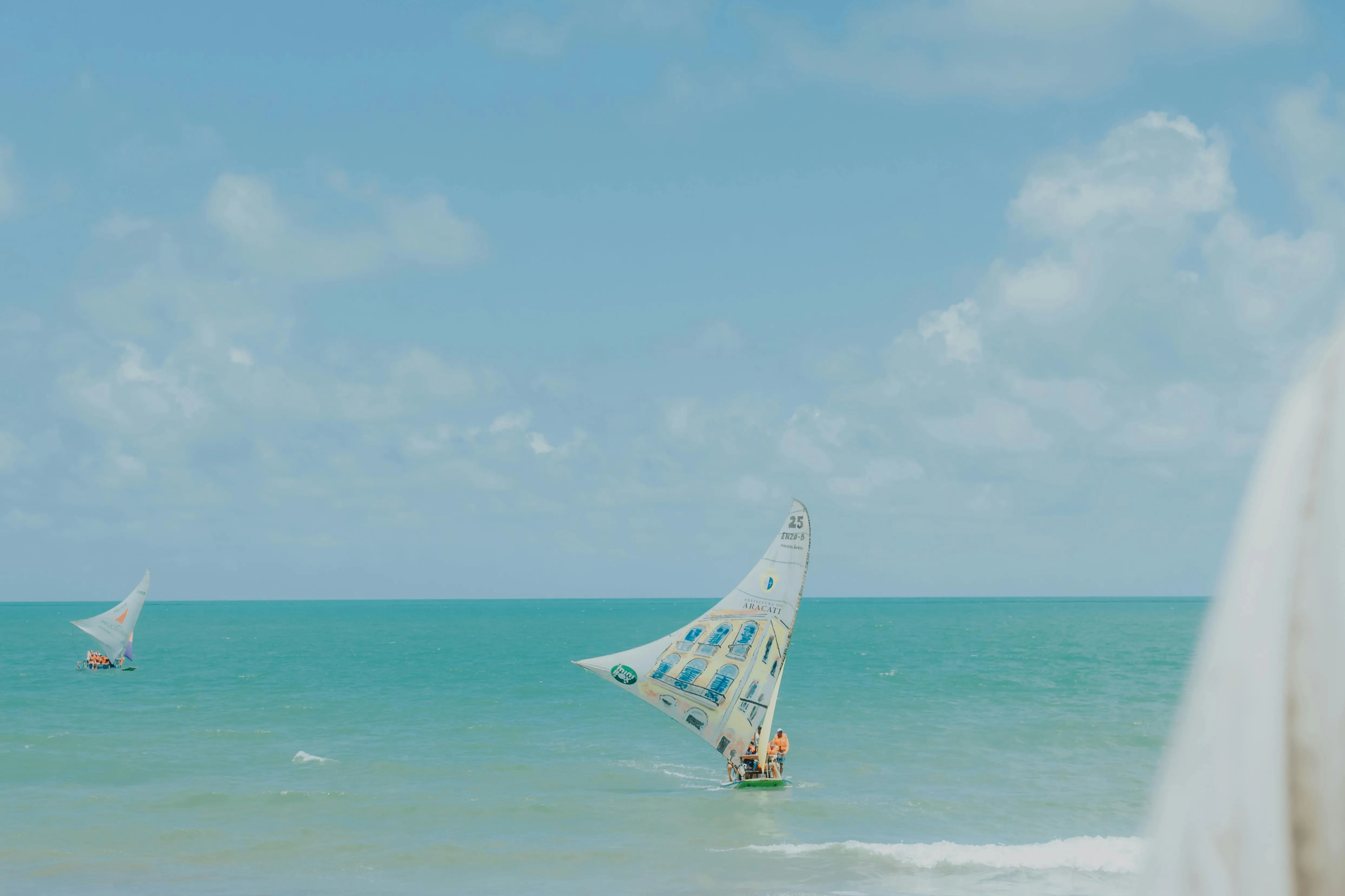 Traditional jangadas under red cotton sails off the turquoise Majorlândia coast, the fleet that still puts out at dawn from Ceará's beaches.
